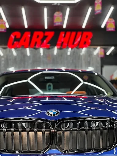 Close-up of a blue BMW bonnet and grille reflecting the Carz Hub studio lights