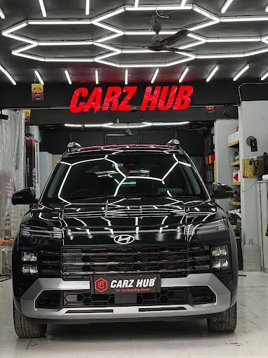 Black Hyundai beneath the Carz Hub sign and hexagonal studio lights